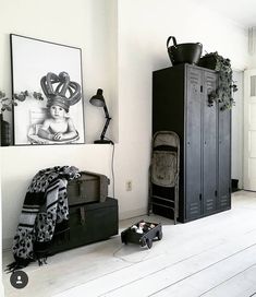 a black locker sitting next to a white wall in a room with hard wood flooring