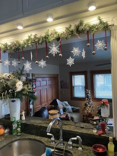 a kitchen decorated for christmas with snowflakes hanging from the ceiling and decorations on the counter