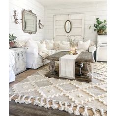 a living room filled with white furniture and pillows on top of a wooden coffee table