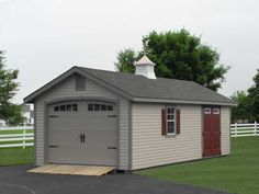 a garage with two doors on the side and a shed in the back ground next to it