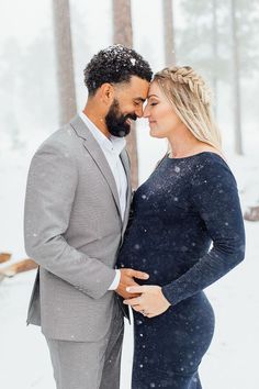 a pregnant couple standing in the snow