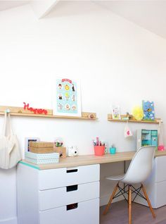 a white desk and chair in a small room with shelves on the wall above it