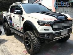 a white truck parked in front of a building with checkered stripes on the side