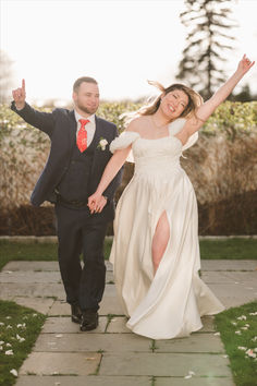 a bride and groom are walking down the sidewalk