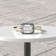 two engagement rings sitting on top of a white table next to a brick sidewalk area