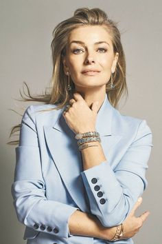 a woman in a blue suit with her hands on her chest and looking at the camera