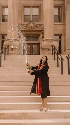 a woman is standing on some steps and throwing water into the air with her hands