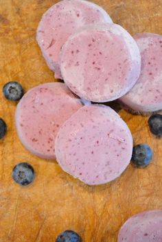 blueberries and ice cream are sitting on a cutting board next to some cut up meat