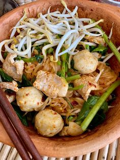 a bowl filled with noodles, meat and veggies next to chopsticks