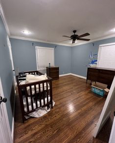 a baby's room with blue walls and wood floors, including a crib