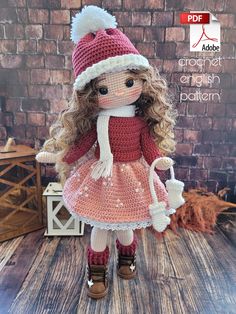 a crocheted doll wearing a red dress and hat with white pom poms