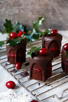 small chocolate cakes with cherries and holly on a cooling rack for holiday desserts