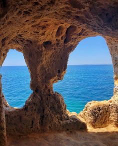 the view from inside a cave looking out at the ocean and blue sky in the distance