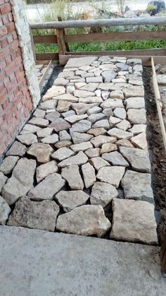 a walkway made out of stones next to a brick wall