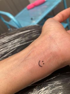 a person's arm with a smiley face tattoo on the left side of their wrist