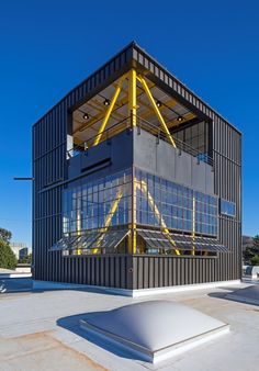 the building is made out of shipping containers and has yellow beams on it's roof