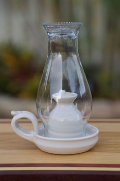 a glass pitcher sitting on top of a wooden table next to a white saucer