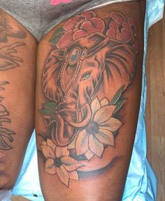 an elephant tattoo on the back of a woman's thigh, with flowers around it