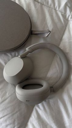 a pair of headphones sitting on top of a bed next to a round object