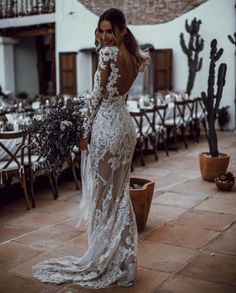 a woman in a white wedding dress standing on a patio next to a cactus plant