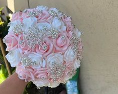 a bridal bouquet is being held up against a wall by someone's hand