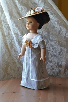 a doll wearing a dress and hat with flowers on it's head, standing on a wooden table