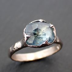 a close up of a ring with a blue topazte in the center on a black surface