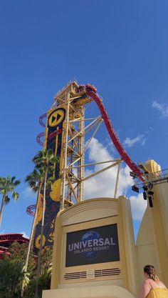 a roller coaster at universal studios with a woman in yellow dress looking up from it