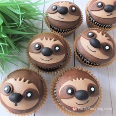 four cupcakes with chocolate frosting decorated to look like slotty faces and noses