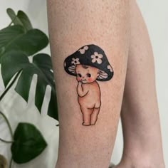 a person with a tattoo on their leg wearing a mushroom hat and holding her hand up to the side