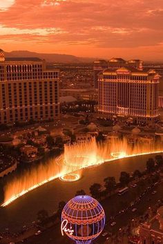 an aerial view of the las vegas strip and fountains at sunset, with buildings in the background