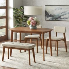 a dining room table with two chairs and a bench in front of a painting on the wall