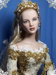 a barbie doll wearing a gold and white dress with long blonde hair in front of a blue background