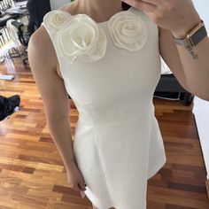 a woman taking a selfie with her cell phone wearing a white dress and flowers