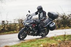 a man riding on the back of a motorcycle down a curvy country road