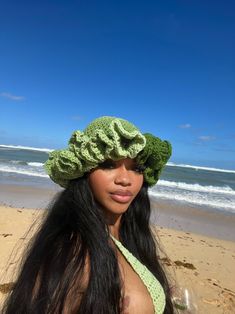 a woman wearing a green crochet hat on the beach