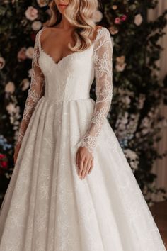 a woman wearing a wedding dress with long sleeves