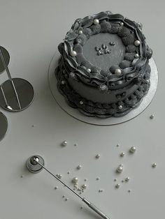 there is a cake that has been decorated with pearls and silver decorations on the table