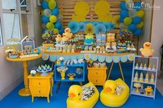 a yellow rubber ducky is sitting in front of a blue and yellow dessert table