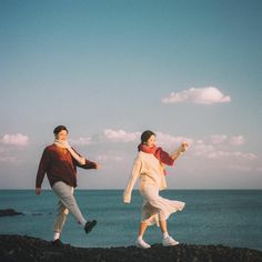 two people are running on the beach near the water