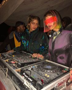 two people standing next to each other in front of a dj's equipment