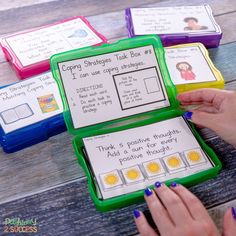 a person holding a green box with four cards in it on top of a wooden table