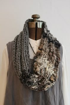 a woman wearing a gray sweater and grey scarf on top of a mannequin