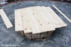 a fire pit made out of wooden planks on top of cement and surrounded by snow