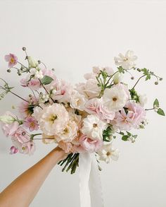 a bouquet of pink and white flowers being held by someone's hand