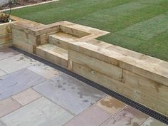 a wooden bench sitting on top of a stone walkway next to a lush green field