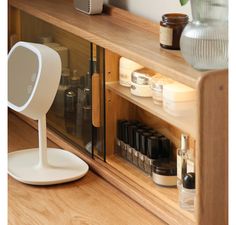 an electronic device is sitting on top of a wooden shelf next to bottles and jars