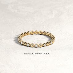 a yellow gold ring with five round beads on it, sitting on a white surface