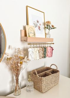 there is a basket on the table next to a mirror and vase with flowers in it