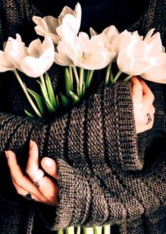 a woman holding flowers in her hands with white tulips on the other side